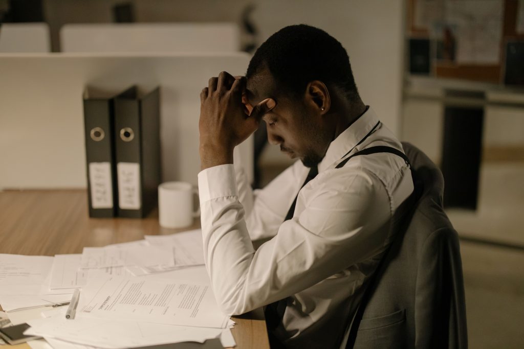 A stressed business executive sitting at an office desk holding his head in his hands, highlighting operational friction and heavy administrative workloads in Raleigh enterprises.